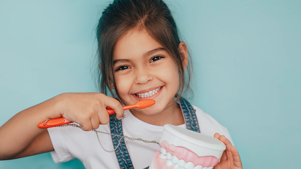 Girl with toothbrush and oversized plastic teeth